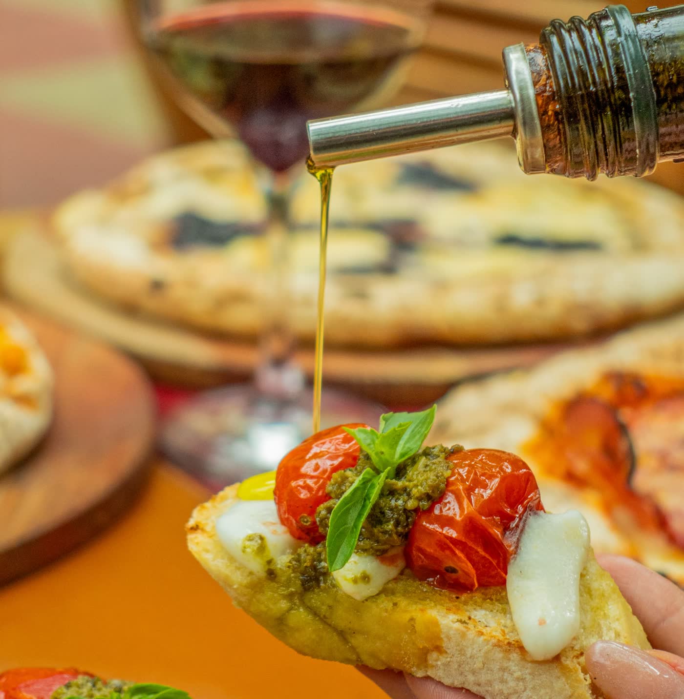 Olive oil poured over a bruschetta with pesto and confit tomatoes